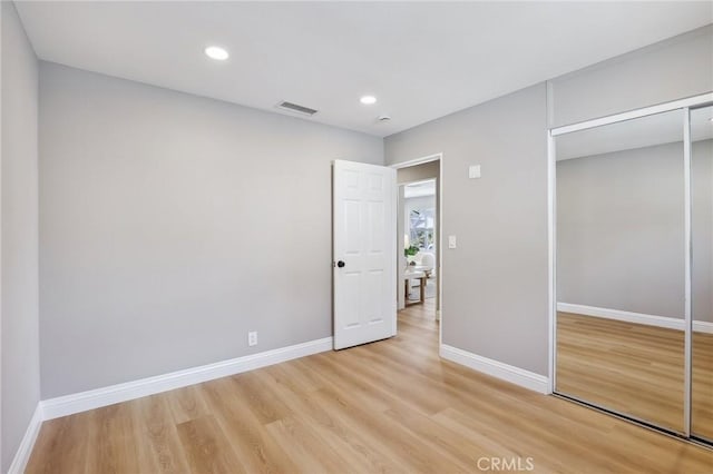 unfurnished bedroom with a closet, baseboards, visible vents, and light wood-type flooring