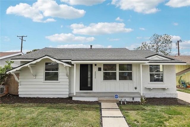bungalow featuring board and batten siding, a shingled roof, a porch, and a front lawn