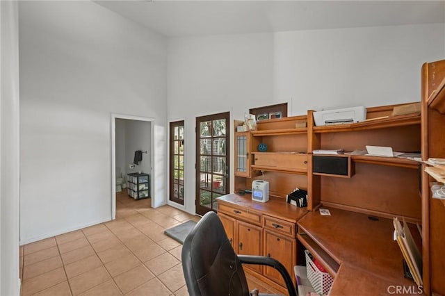 office space with baseboards, light tile patterned floors, and a high ceiling