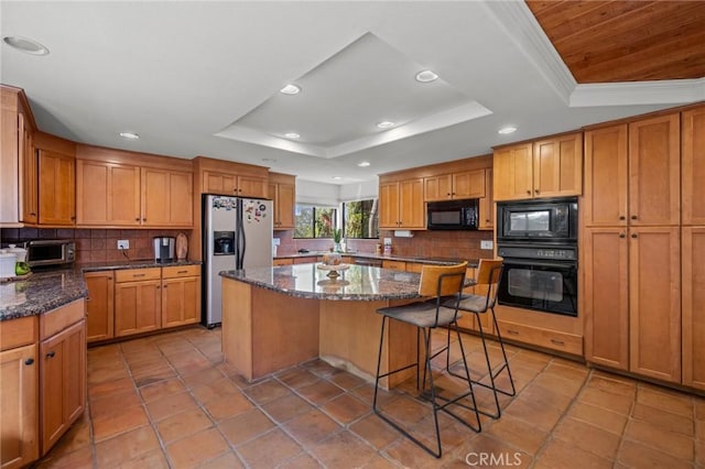 kitchen featuring black appliances, a kitchen island, a raised ceiling, and tasteful backsplash