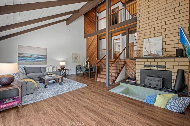 living area with high vaulted ceiling, beamed ceiling, wood finished floors, and stairway
