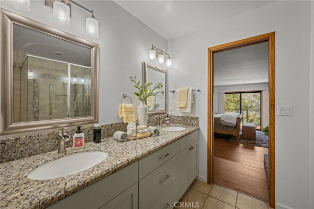 bathroom featuring double vanity, a shower stall, tile patterned floors, and a sink