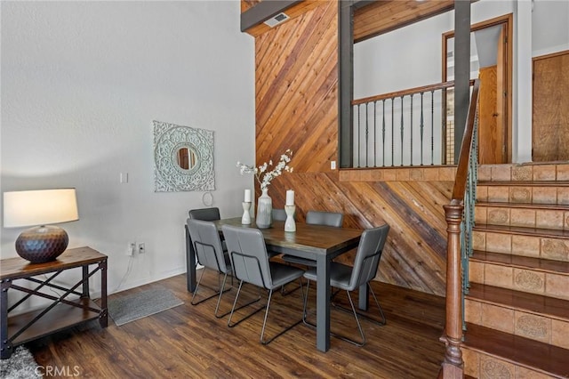 dining space featuring baseboards, stairway, wood finished floors, and wooden walls