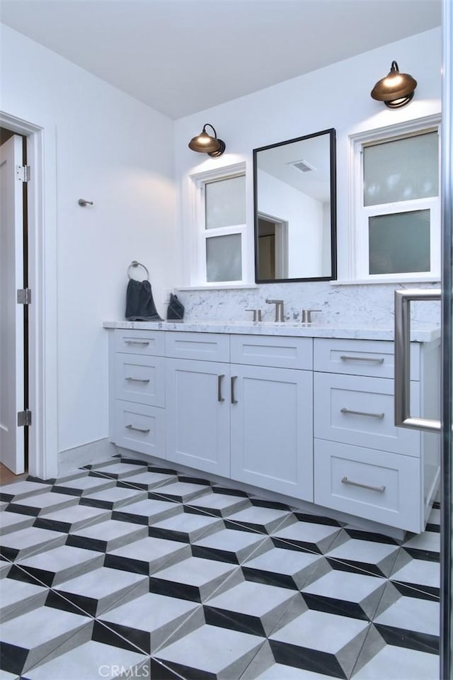bathroom featuring visible vents, vanity, and decorative backsplash