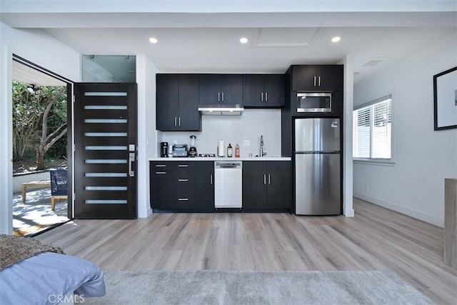 kitchen featuring light wood finished floors, dark cabinets, and stainless steel appliances