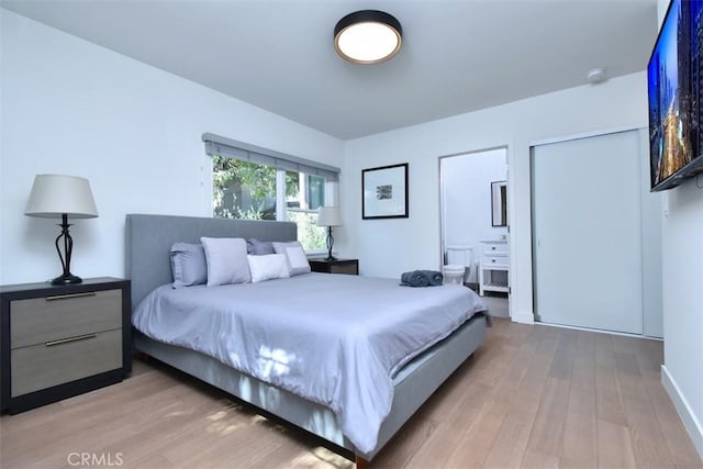 bedroom featuring light wood-type flooring and ensuite bath