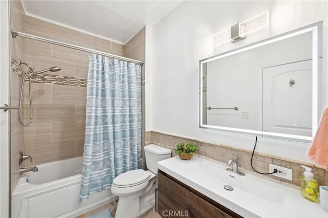 bathroom with shower / bath combo, toilet, tile walls, vanity, and wainscoting