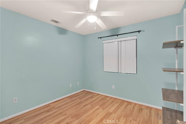 empty room with visible vents, ceiling fan, wood finished floors, and baseboards