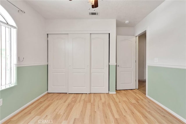 unfurnished bedroom featuring visible vents, baseboards, a closet, wood finished floors, and a ceiling fan