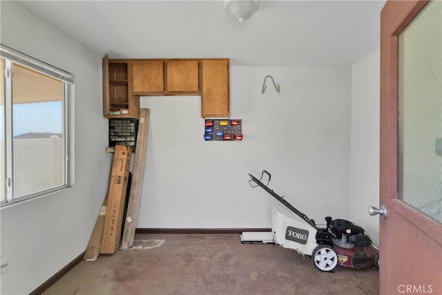 interior space with concrete floors, brown cabinetry, and baseboards