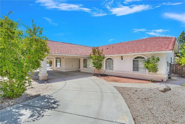 view of front of home featuring driveway, a carport, a tiled roof, and stucco siding