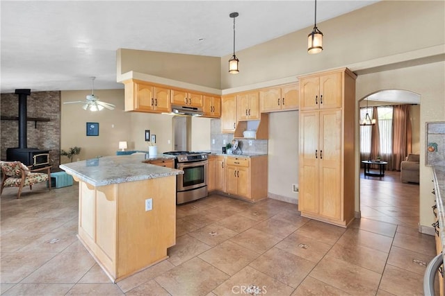 kitchen featuring arched walkways, stainless steel range with gas stovetop, a peninsula, and light brown cabinets