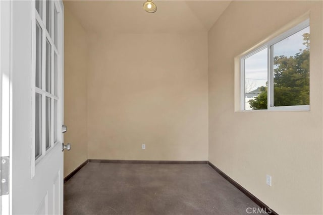unfurnished room featuring baseboards and finished concrete flooring