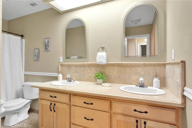 bathroom with visible vents, toilet, double vanity, and a sink