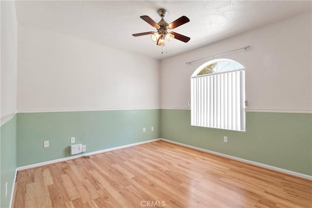 empty room with wood finished floors, ceiling fan, and baseboards