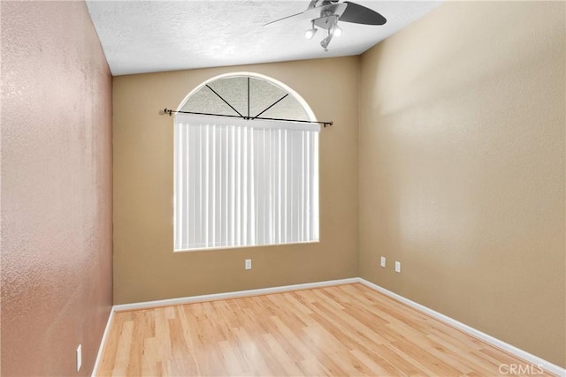 unfurnished room featuring a ceiling fan, wood finished floors, and baseboards