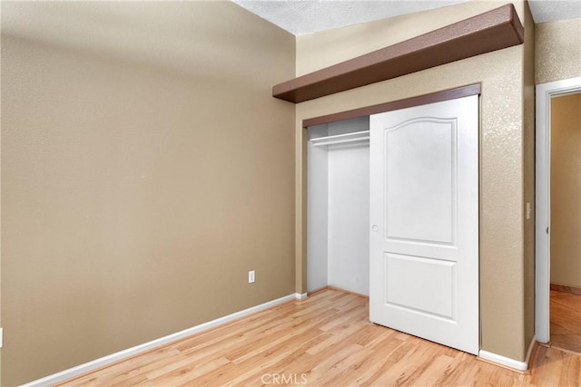 unfurnished bedroom featuring a closet, baseboards, and light wood-type flooring