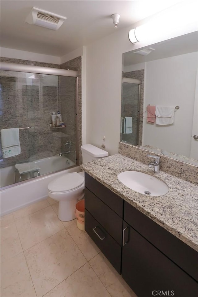 bathroom with vanity, toilet, visible vents, enclosed tub / shower combo, and tile patterned flooring