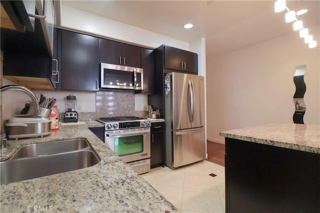 kitchen with recessed lighting, light stone countertops, a sink, stainless steel appliances, and light tile patterned floors