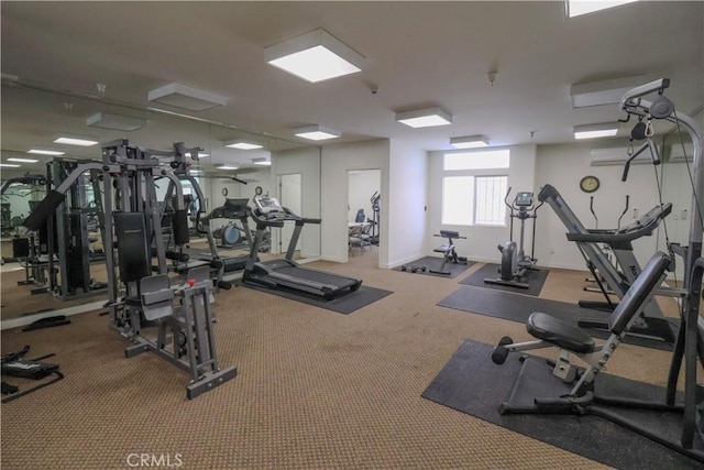 exercise room with an AC wall unit, carpet floors, and baseboards