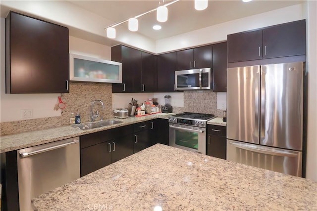 kitchen featuring light stone counters, appliances with stainless steel finishes, decorative backsplash, and a sink