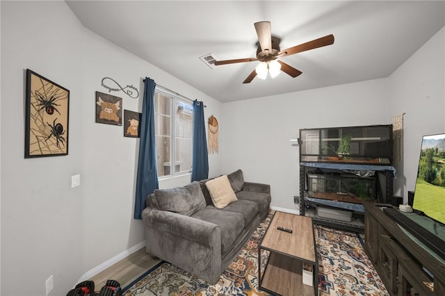 living room featuring baseboards, visible vents, wood finished floors, and a ceiling fan