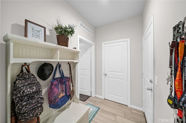 mudroom featuring baseboards, visible vents, and wood finish floors