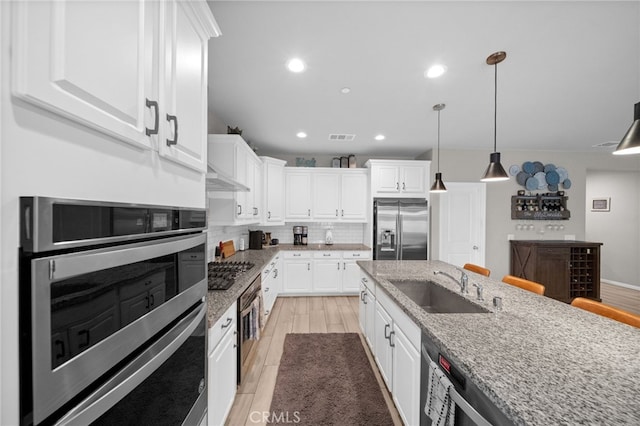 kitchen with a sink, white cabinets, stainless steel appliances, and decorative backsplash