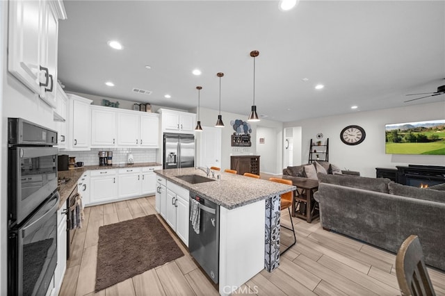 kitchen with a sink, visible vents, backsplash, appliances with stainless steel finishes, and open floor plan