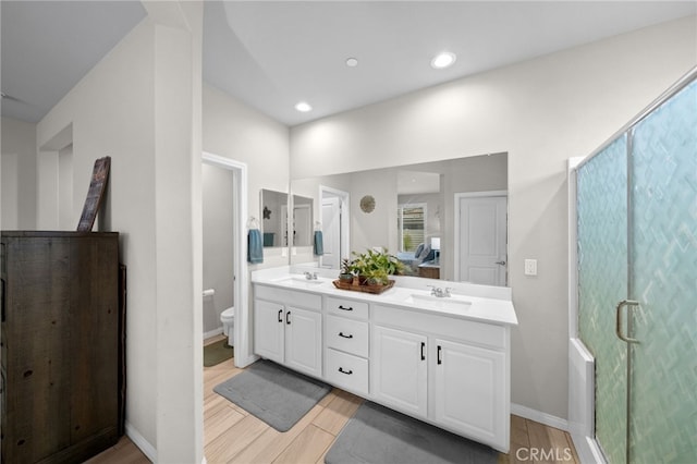 bathroom with double vanity, wood finished floors, toilet, and a sink