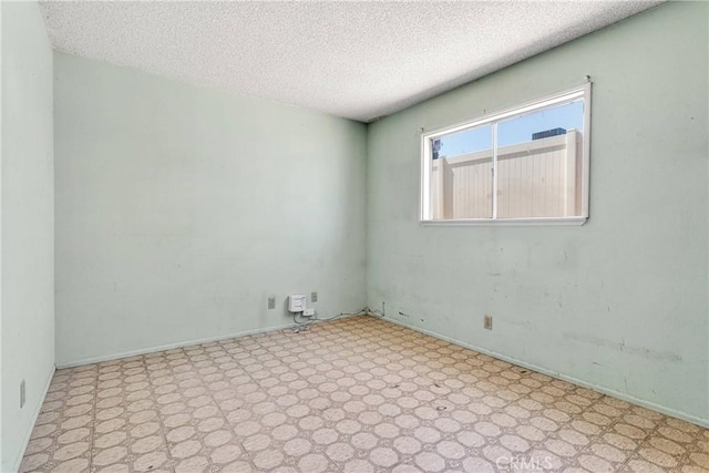 unfurnished room with baseboards and a textured ceiling