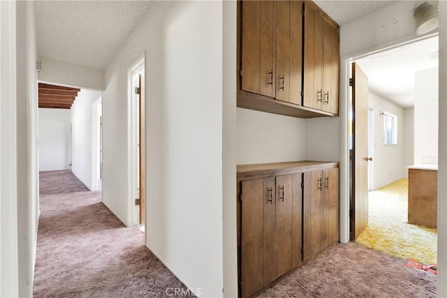 corridor featuring a textured ceiling and light colored carpet