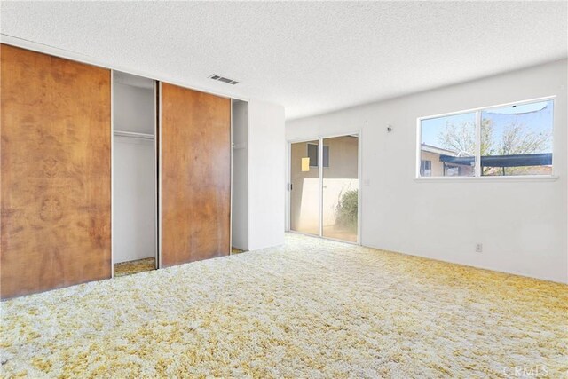 unfurnished bedroom with visible vents, a textured ceiling, and carpet flooring