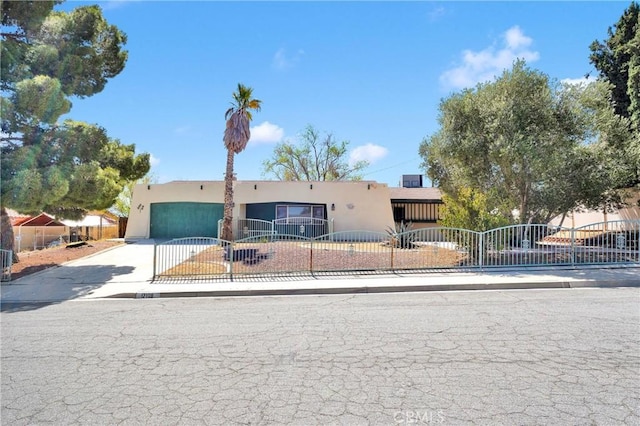 view of front of home featuring stucco siding, a garage, concrete driveway, and a fenced front yard