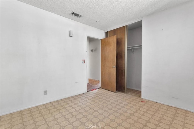 unfurnished bedroom featuring light floors, a closet, baseboards, visible vents, and a textured ceiling