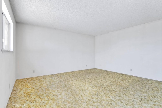 carpeted empty room featuring a textured ceiling