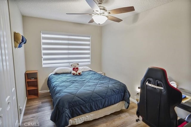 bedroom with a textured ceiling, wood finished floors, a ceiling fan, and baseboards