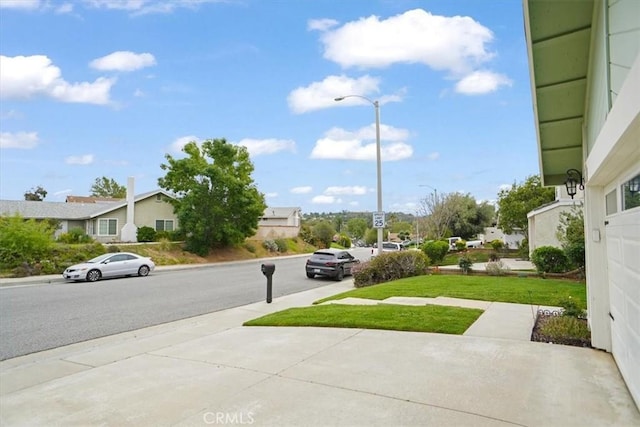 view of street featuring sidewalks, street lights, and a residential view