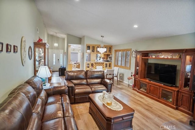 living area with light wood-type flooring, an inviting chandelier, lofted ceiling, and recessed lighting