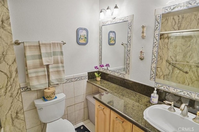 bathroom featuring vanity, toilet, a wainscoted wall, and tile walls