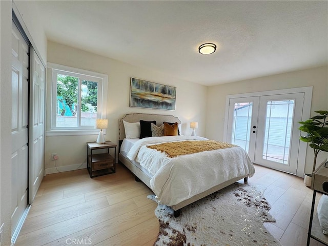 bedroom featuring baseboards, french doors, light wood-type flooring, and access to exterior