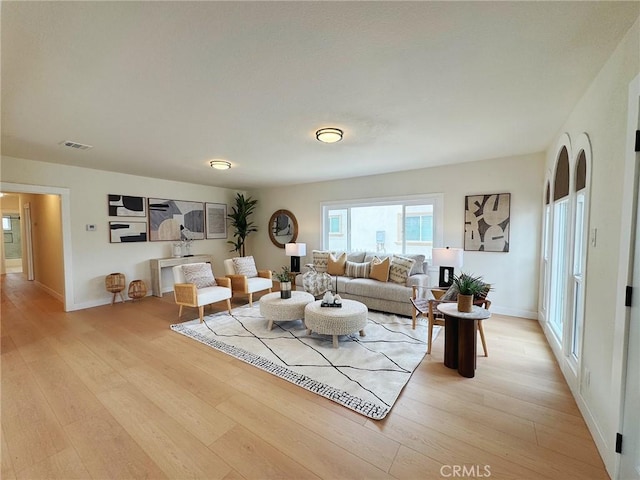 living area featuring visible vents, light wood-style flooring, and baseboards