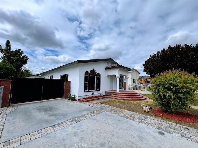 ranch-style house featuring concrete driveway, fence, a gate, and stucco siding