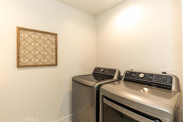 clothes washing area with baseboards, washer and clothes dryer, and laundry area