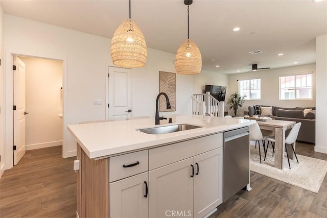 kitchen featuring decorative light fixtures, stainless steel dishwasher, dark wood finished floors, and a sink