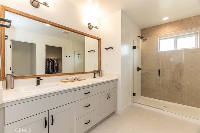 full bath featuring tile patterned floors, a stall shower, double vanity, and a sink