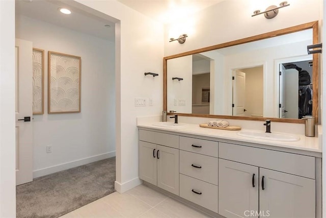 bathroom featuring double vanity, a sink, tile patterned floors, and baseboards