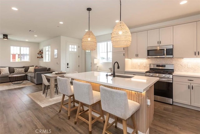 kitchen featuring dark wood-style flooring, appliances with stainless steel finishes, light countertops, and a sink