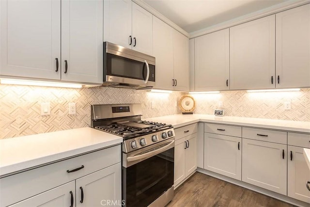 kitchen with backsplash, dark wood-style flooring, appliances with stainless steel finishes, and light countertops