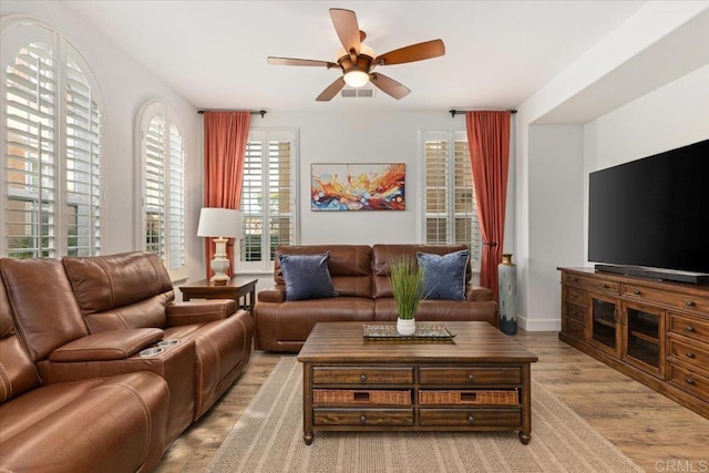 living room with visible vents, ceiling fan, and light wood-style flooring